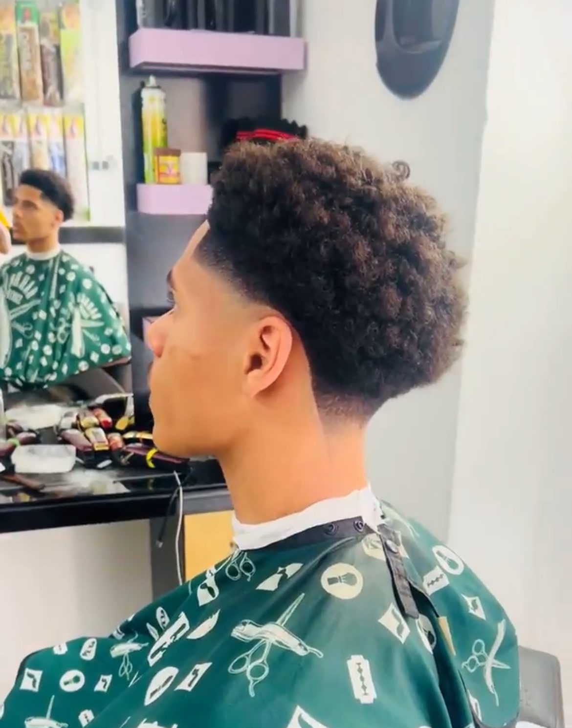 Client with a low fade and curly top in the chair at Gentle Touch